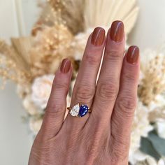 a woman's hand with a blue and white diamond ring on her left hand