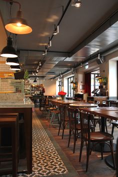 an empty restaurant with tables and chairs in front of the counter, along with lights hanging from the ceiling