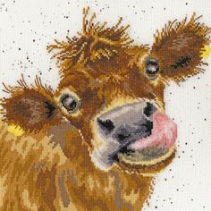 a close up of a cross stitch pattern of a brown cow with it's tongue out