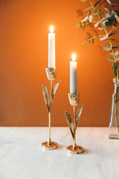 two candles sitting on top of a table next to a vase with flowers in it