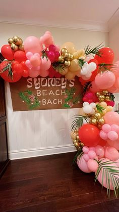 an arch made out of balloons and palm leaves is displayed in front of a sign that says sydney's beach