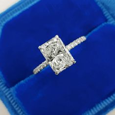 a diamond ring sitting on top of a blue velvet case