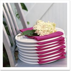 a stack of plates with flowers on them sitting on a table next to a chair