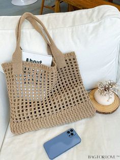 a cell phone sitting on top of a white couch next to a crocheted bag