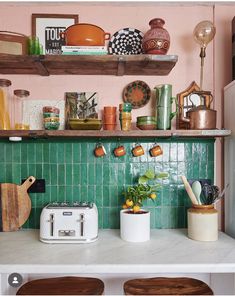 a kitchen with green tile and wooden shelves