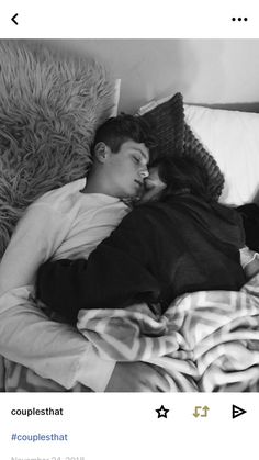 a man and woman sleeping on a bed next to each other in black and white