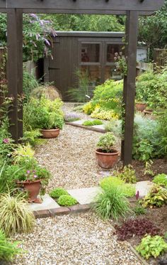 an outdoor garden with lots of plants and flowers in the center, surrounded by gravel