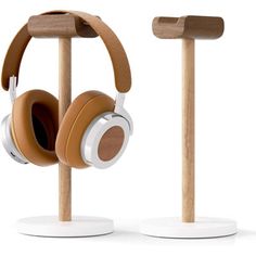 two wooden headphones are on display with ear phones attached to the stands and one is white