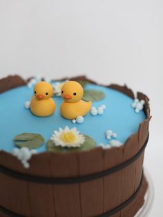 two rubber ducks floating on top of a blue and brown cake