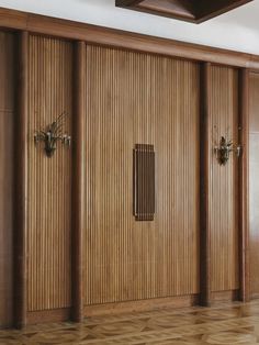 an empty room with wooden paneling and two vases on the wall next to it