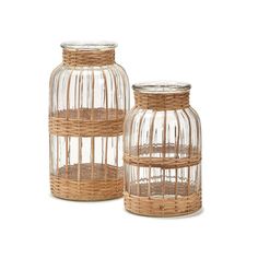 two glass vases with wicker handles on each one and an empty jar in the middle