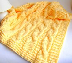 a yellow knitted blanket sitting on top of a white table next to a lamp