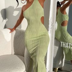 a woman in a green dress standing next to a mirror