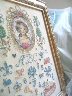 a cross stitch picture frame sitting on top of a bed