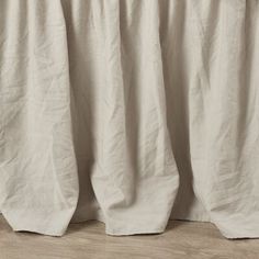 a white curtain is hanging on the side of a wooden wall with wood flooring