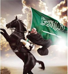 a man riding on the back of a black horse next to a green and white flag