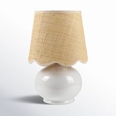 a white table lamp with a beige shade on it's top and bottom half