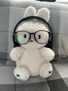 a white teddy bear wearing headphones sitting on a couch