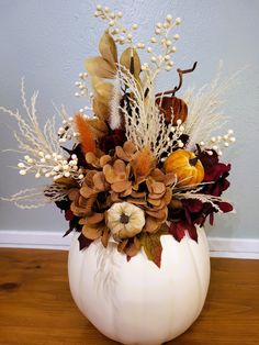 a white pumpkin decorated with dried flowers and leaves