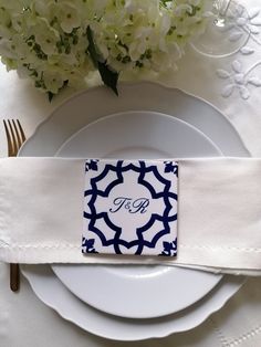 a place setting with white and blue napkins, silverware and hydrangeas