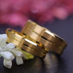 two wedding rings sitting next to each other on top of a table with white flowers