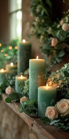 candles are lined up on a mantle with greenery