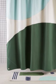 a shower curtain with green and white stripes on it, next to a bathtub