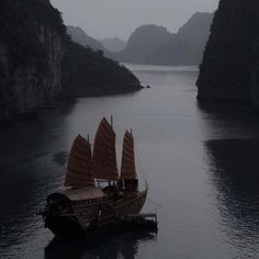 a boat floating on top of a large body of water next to tall mountains in the distance