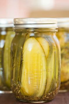 three jars filled with pickles sitting on top of a table