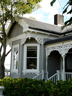 a grey house with white trim on the front porch and stairs leading up to it