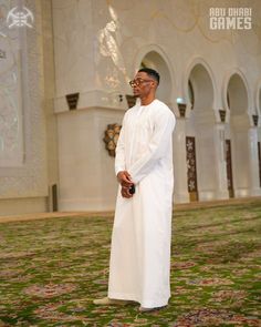 a man is standing in the middle of a room with green carpet and white walls