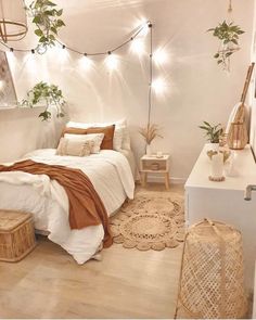 a bedroom with white walls and wooden flooring has plants on the wall above the bed