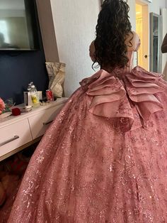 a woman is getting her hair styled in a pink gown with large ruffles