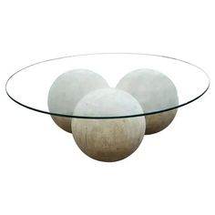 three white balls sitting on top of a glass table in front of a white background