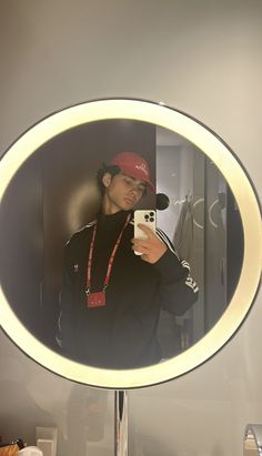 a man taking a selfie in front of a mirror with his cell phone and hat on