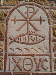 a stone wall with a fish and cross on it