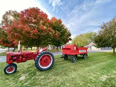 an old red tractor is parked in the grass