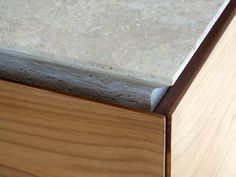 a close up view of the top of a wooden cabinet with marble and wood trim