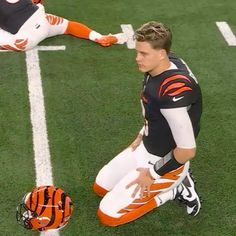 a man kneeling down on top of a field next to a football helmet and glove