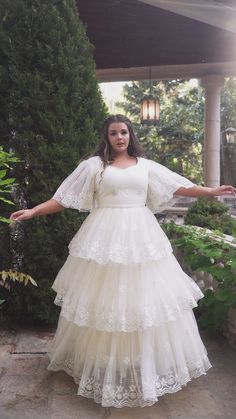 a woman in a white dress is posing for the camera with her arms spread out