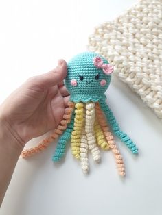 a crocheted octopus stuffed animal being held by someone's hand on a white surface