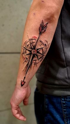 a man's arm with a compass tattoo on it and an arrow in the middle