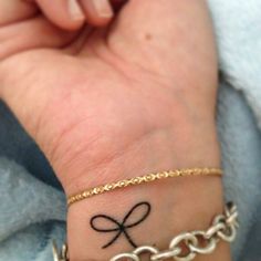 a person's wrist with a tattoo on it and a chain around the wrist