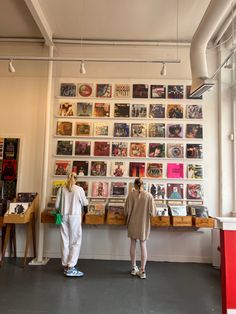 two people standing in front of a wall with pictures on it