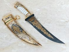 two different types of knifes sitting on top of a white surface with gold trimming