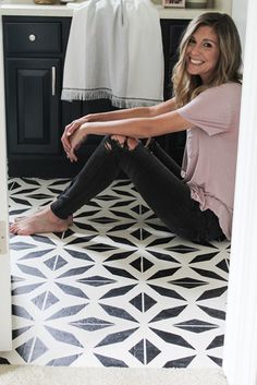 a woman sitting on the floor in her bathroom