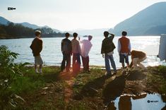 four people standing on the shore of a lake