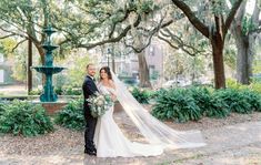 a bride and groom standing in front of a fountain