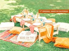 the picnic table is set up with orange and white linens on it, along with pillows