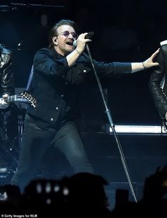 two men on stage with microphones in their hands and one man singing into the microphone